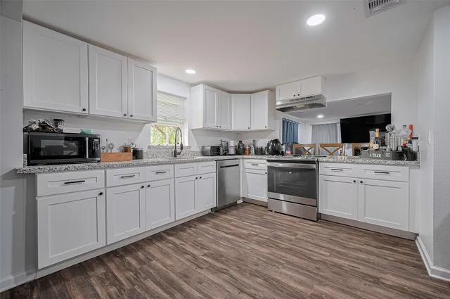 a kitchen with granite countertop white cabinets and white appliances