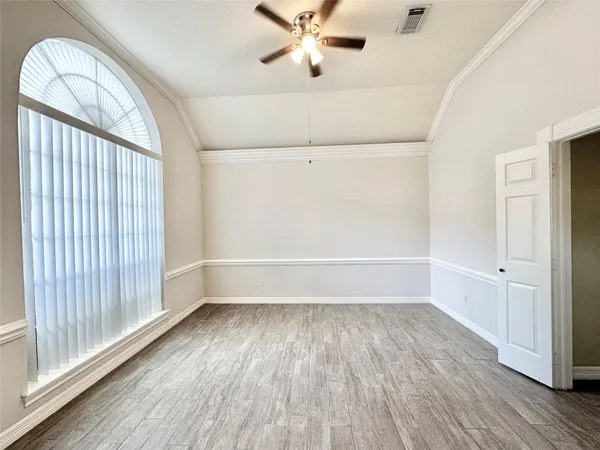 an empty room with wooden floor fan and windows