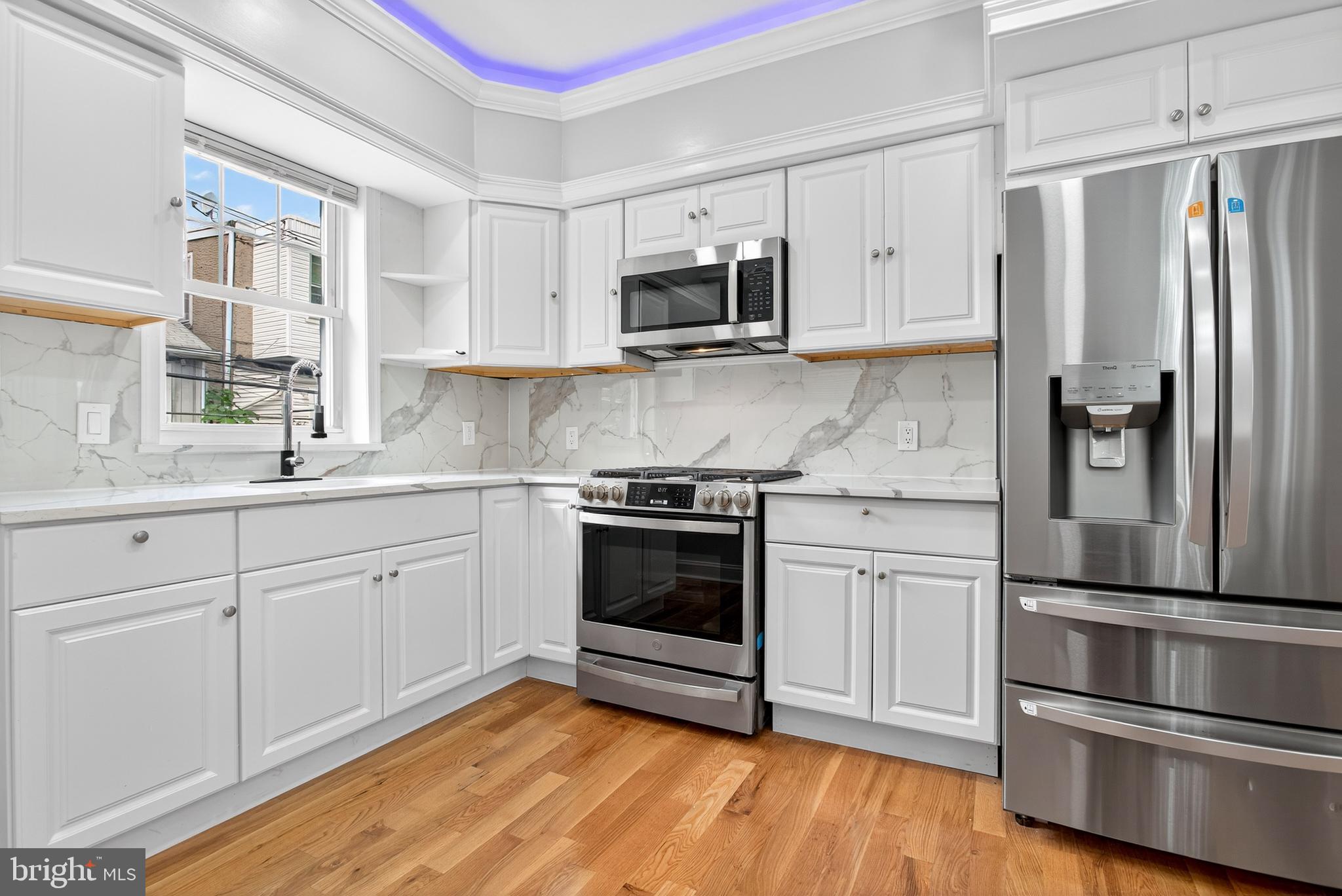 6351 Reedland Street Philadelphia, PA 19142 - Photo 12 of 30 a kitchen with stainless steel appliances white cabinets and wooden floor