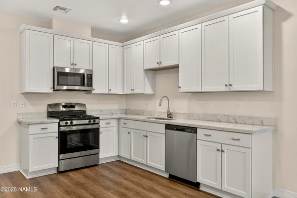 a kitchen with stainless steel appliances granite countertop a stove a sink and a microwave
