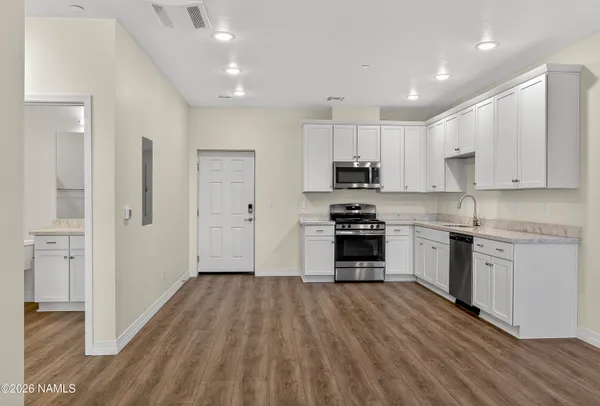 a kitchen with kitchen island wooden floors appliances and cabinets