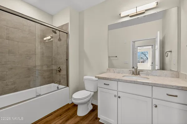 a bathroom with a toilet sink vanity granite and shower