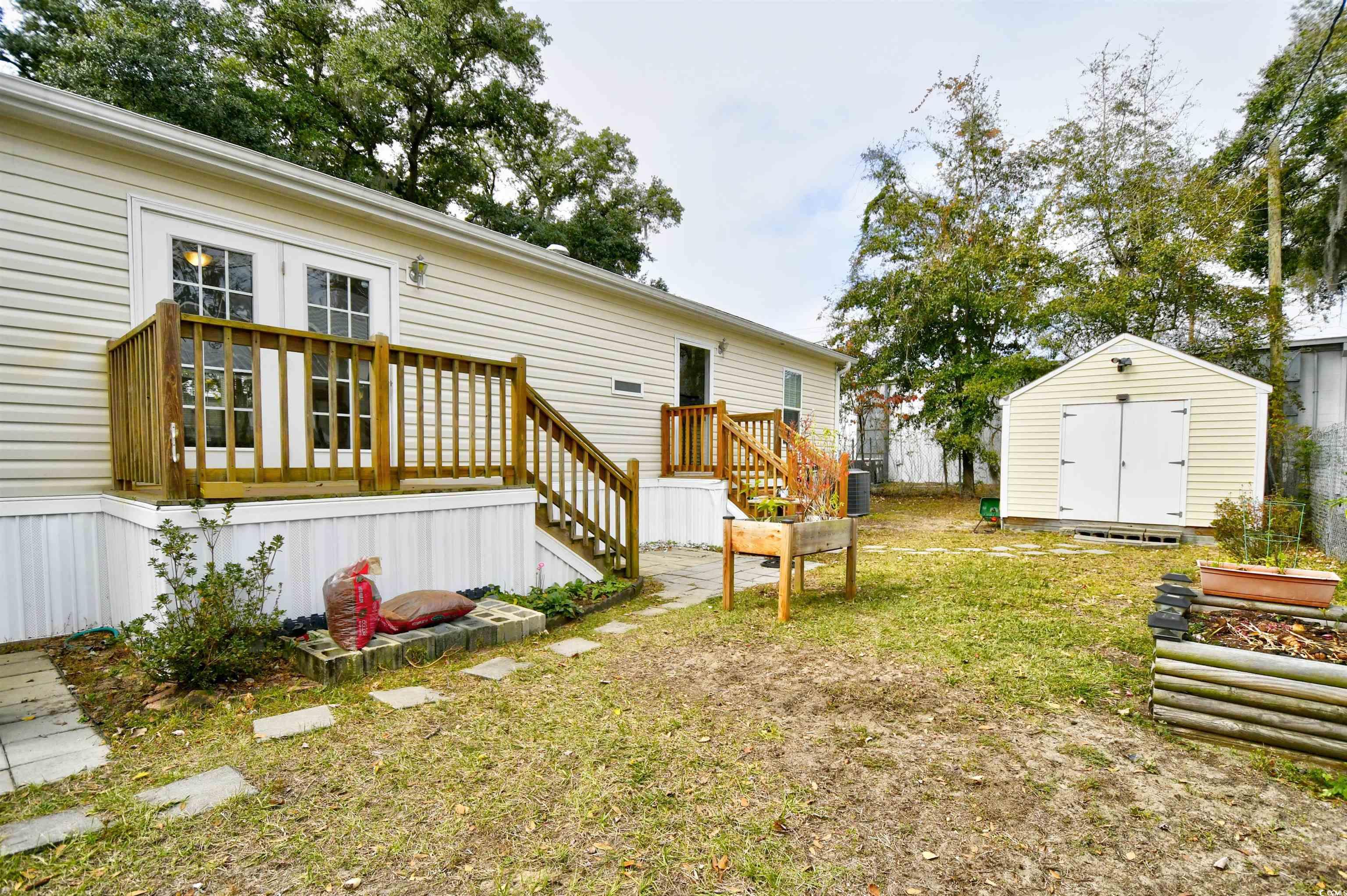 596 Trizzie Trail Murrells Inlet, SC 29576 - Photo 18 of 21 View of green lawn with a storage unit and a deck
