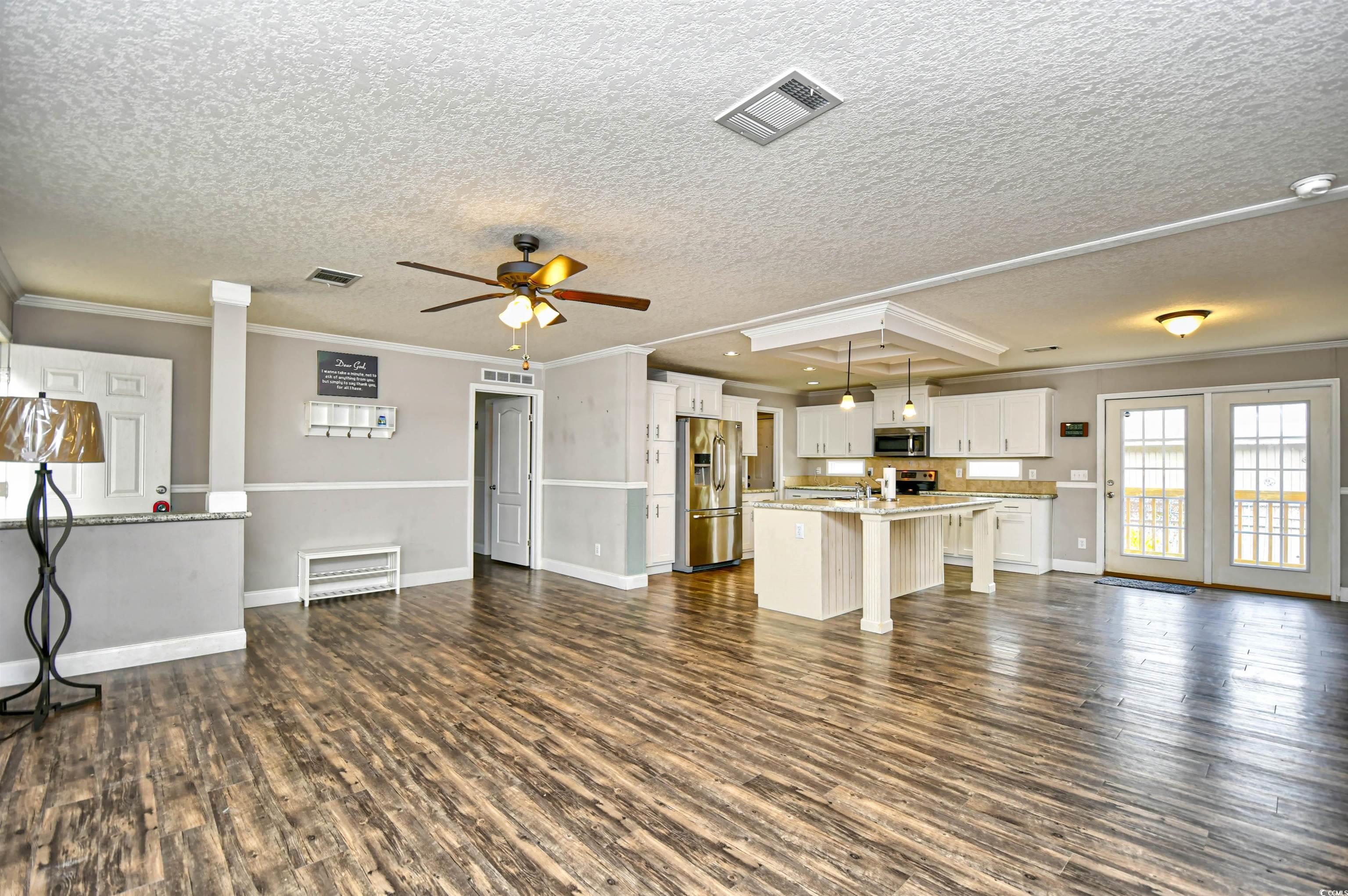 596 Trizzie Trail Murrells Inlet, SC 29576 - Photo 4 of 21 Unfurnished living room featuring dark wood finished floors, ceiling fan, ornamental molding, and a textured ceiling
