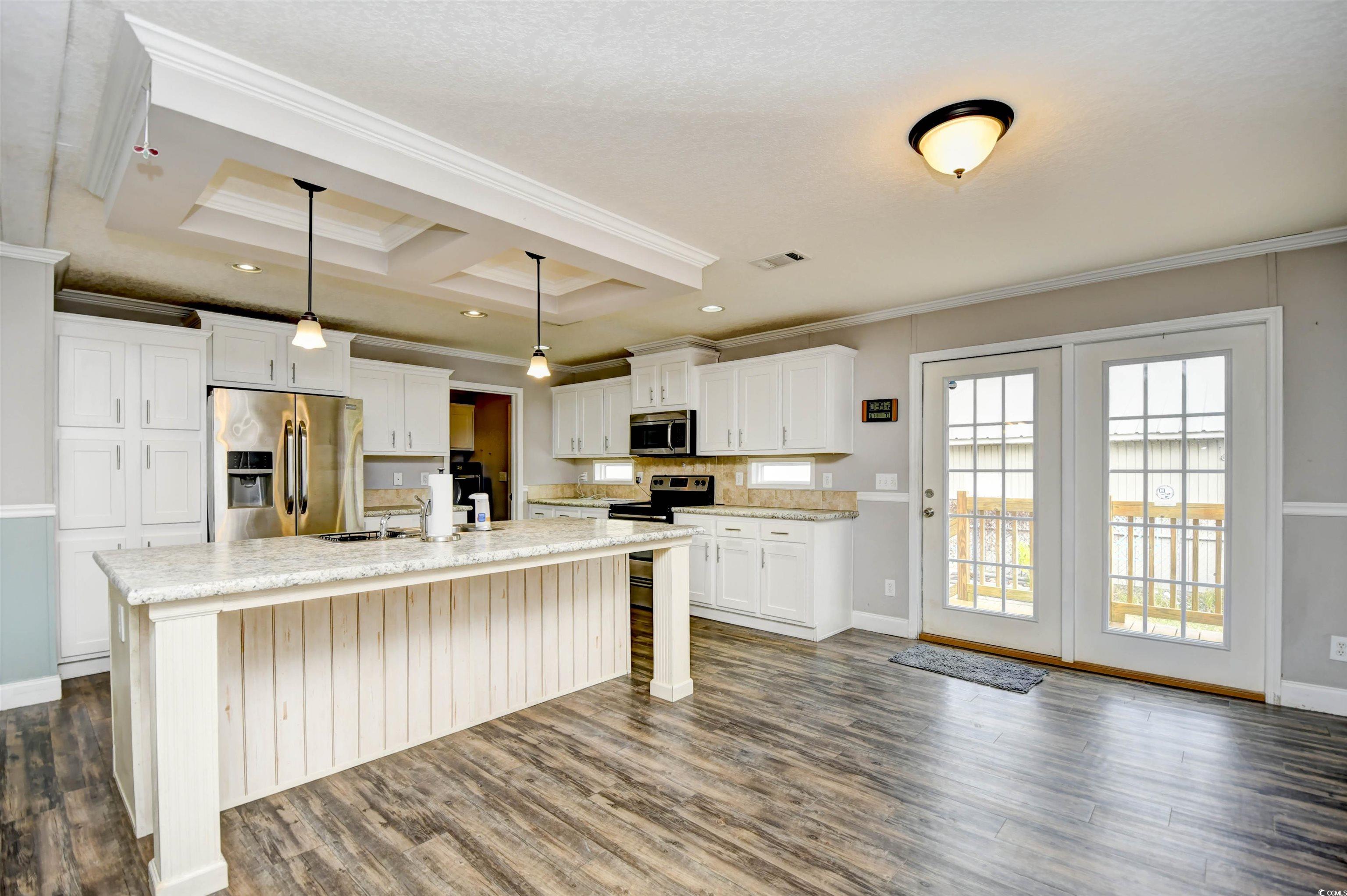 596 Trizzie Trail Murrells Inlet, SC 29576 - Photo 6 of 21 Kitchen with decorative light fixtures, appliances with stainless steel finishes, a center island with sink, white cabinetry, and dark wood finished floors
