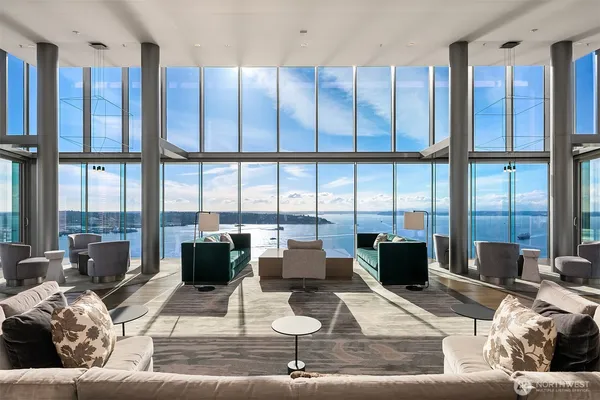 a living room with furniture large windows and wooden floor