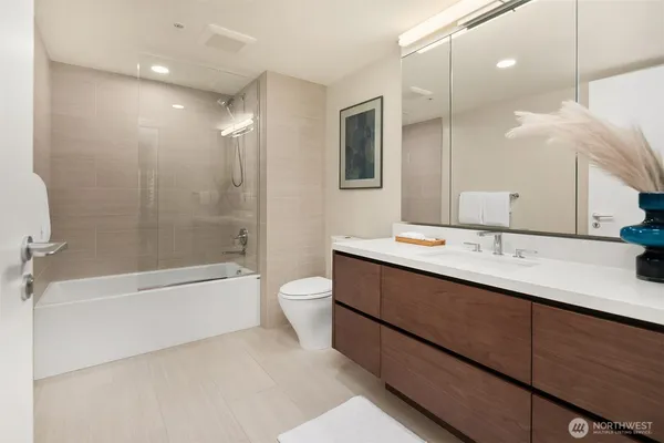 a bathroom with a double vanity sink a toilet and shower