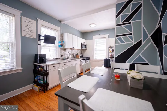 a open kitchen with stainless steel appliances kitchen island granite countertop a sink dishwasher and white cabinets with wooden floor