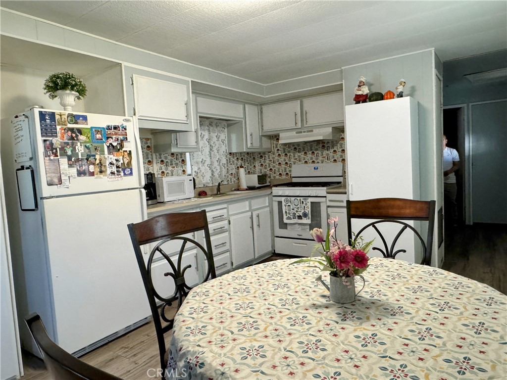 3734 Pacific Street, Unit 40 Highland, CA 92346 - Photo 1 of 15 a kitchen with stainless steel appliances granite countertop a stove a refrigerator a dining table and chairs with wooden floor