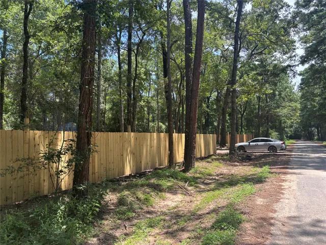 a view of a backyard with large tree and wooden fence