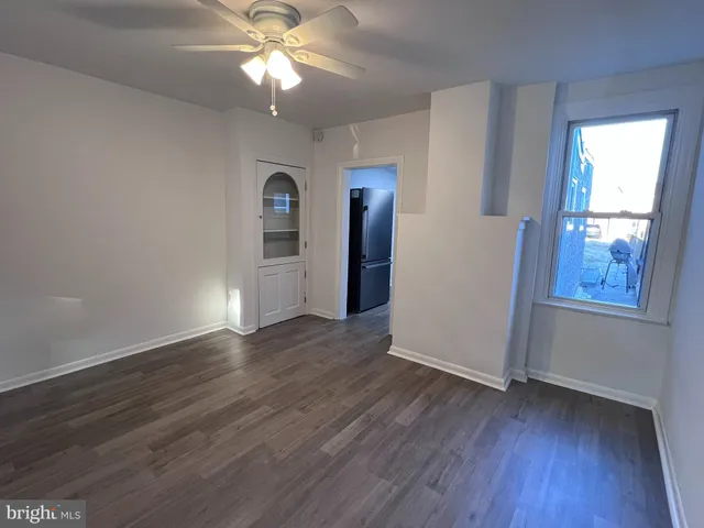 a view of a livingroom with wooden floor a ceiling fan and windows