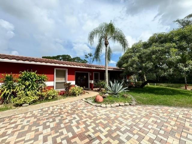 5800 Pine Tree Road Parkland, FL 33067 - Photo 3 of 35 a front view of a house with a yard and potted plants