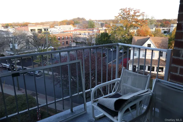 a view of a balcony with wooden chairs and iron fence
