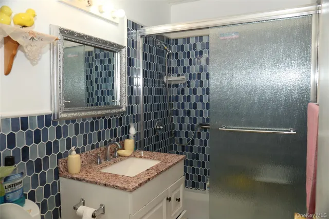 a bathroom with a granite countertop shower a mirror and a sink