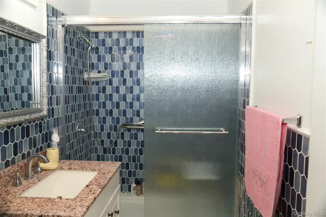 a bathroom with a granite countertop shower a sink and a mirror