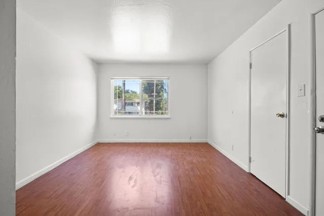an empty room with wooden floor and windows
