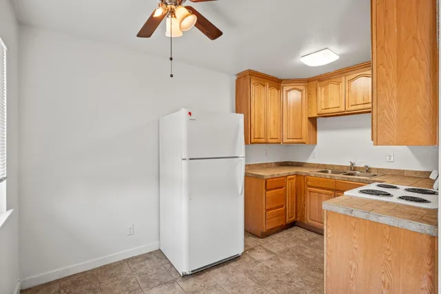 a kitchen with a refrigerator a stove a sink dishwasher and wooden cabinets