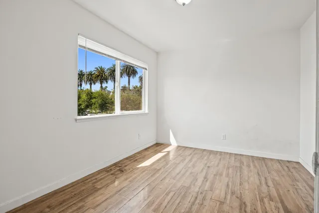 a view of an empty room with wooden floor and a window