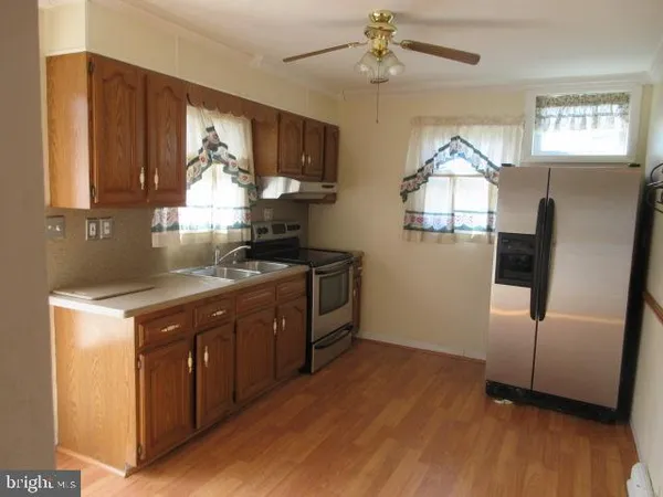 a kitchen with stainless steel appliances granite countertop a refrigerator a sink a stove and wooden floors