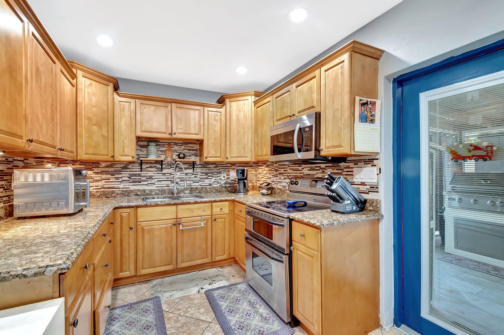 3890 Ocala Road Lake Worth, FL 33462 - Photo 8 of 29 a kitchen with stainless steel appliances granite countertop a stove a sink and a microwave