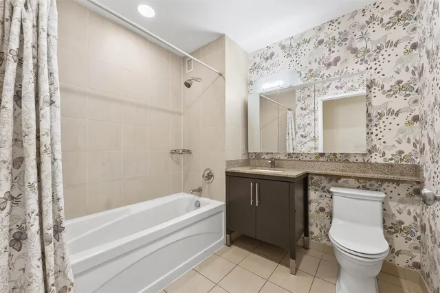 a bathroom with a granite countertop bathtub sink vanity mirror and toilet