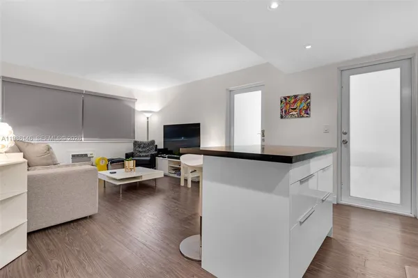 a kitchen with stainless steel appliances granite countertop a refrigerator a stove a sink and white cabinets with wooden floor