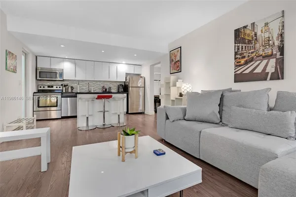 a living room with stainless steel appliances furniture and kitchen view