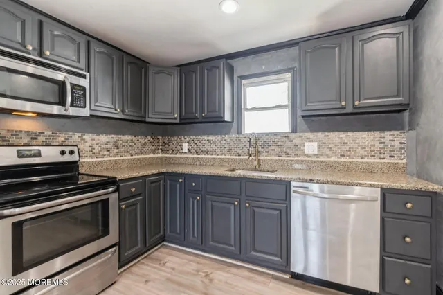 a kitchen with granite countertop cabinets stainless steel appliances and a sink