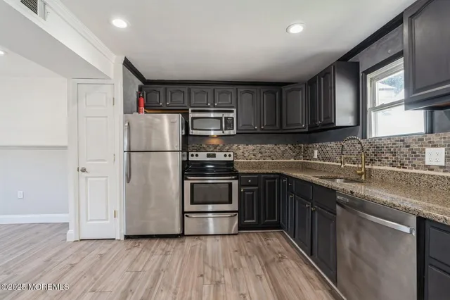 a kitchen with granite countertop a refrigerator stove top oven and sink