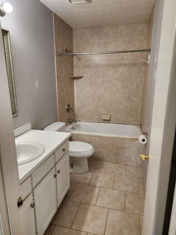 a bathroom with a granite countertop sink a toilet and shower