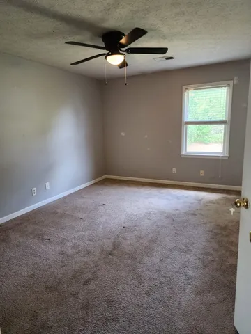 an empty room with a ceiling fan and window