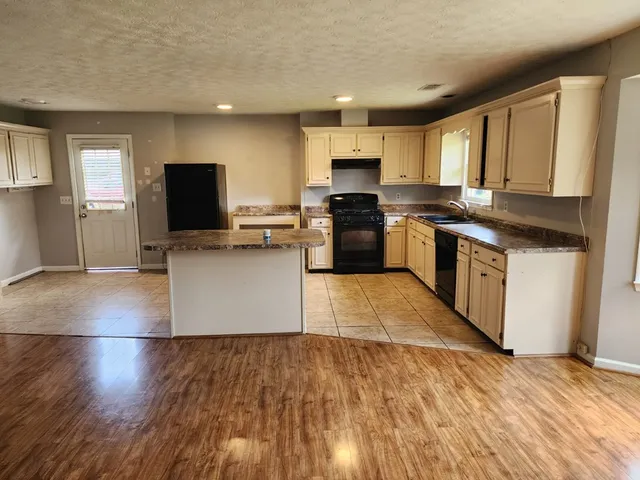 a kitchen with a stove top oven a sink dishwasher and a refrigerator with wooden floor