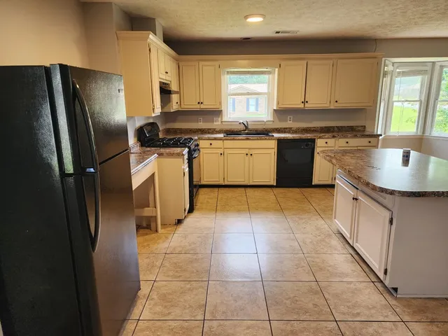 a kitchen with stainless steel appliances granite countertop a stove a sink dishwasher a refrigerator and a oven with wooden floor