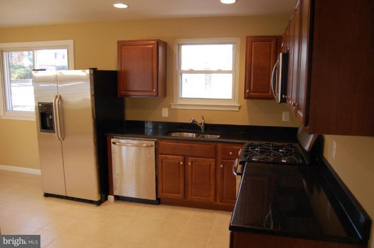 8419 Thames Street Springfield, VA 22151 - Photo 4 of 14 a kitchen with granite countertop white cabinets and refrigerator