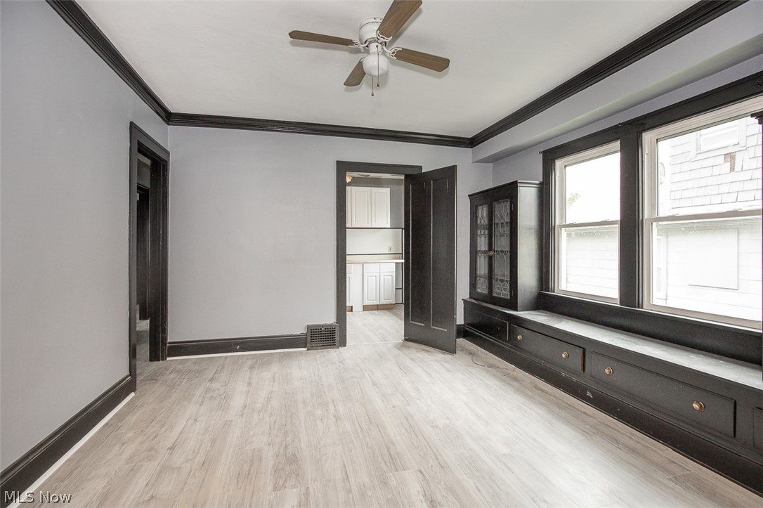 1868-1870 Lampson Road Cleveland, OH 44112 - Photo 7 of 36 Spacious room featuring light wood-finish flooring, a ceiling fan, and dark trim