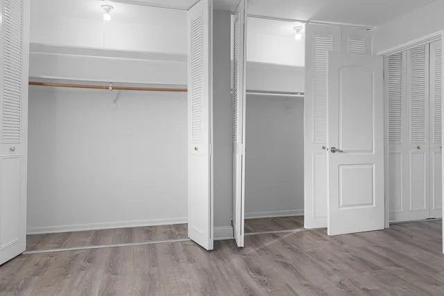 an empty room with wooden floor and closet area