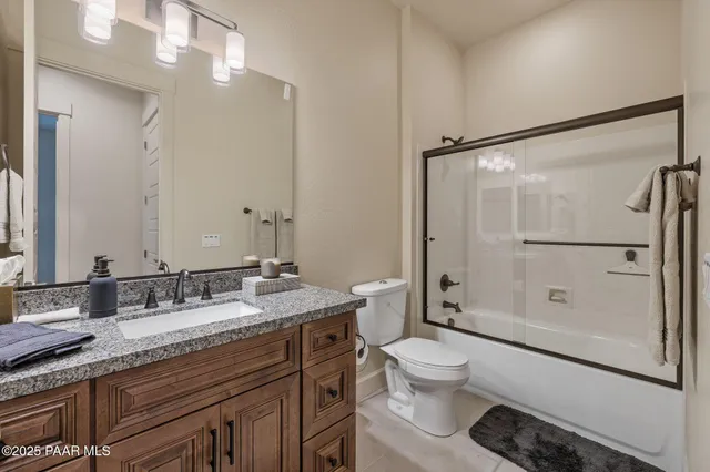 a bathroom with a granite countertop sink toilet mirror and shower