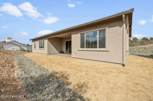 a view of house with backyard and trees in the background