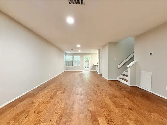 a view of empty room with wooden floor and window