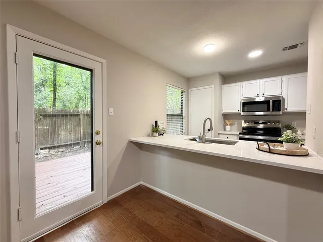 a view of a kitchen with kitchen island a sink wooden floor and a large window