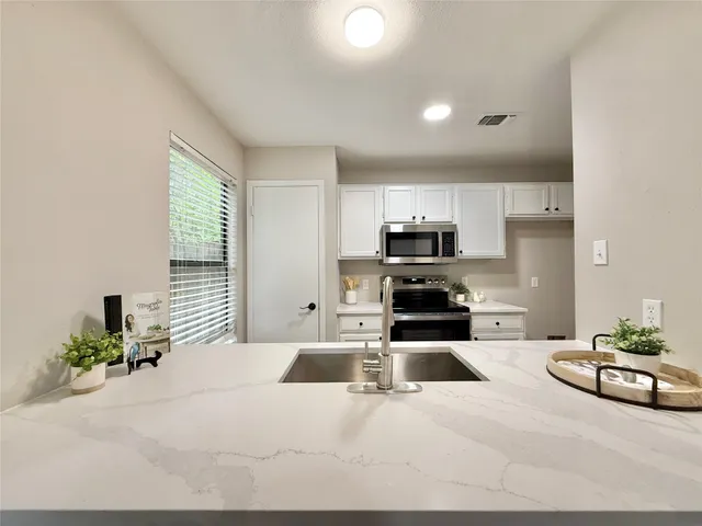 a kitchen with sink a microwave and cabinets