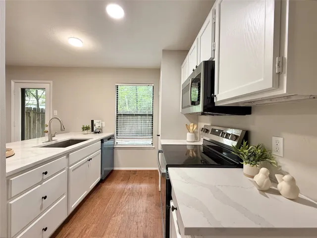 a kitchen with granite countertop a stove a sink and a microwave