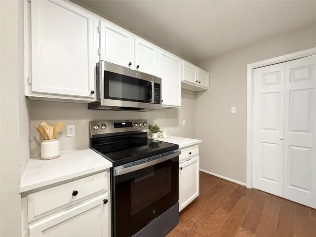 a kitchen with cabinets stainless steel appliances and wooden floor