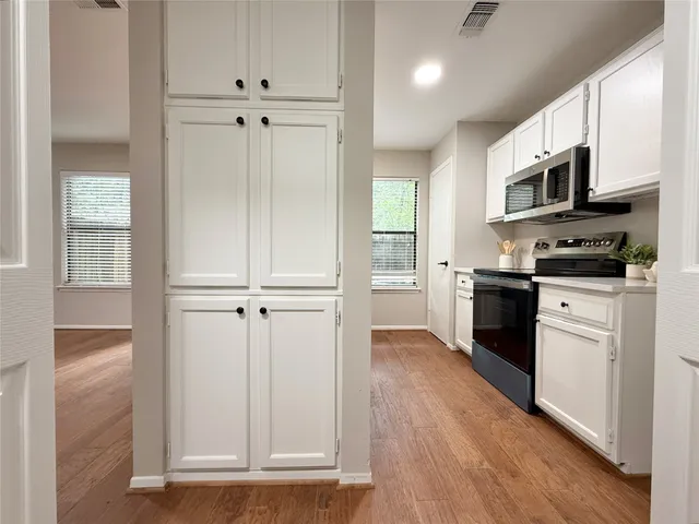 a view of kitchen with stainless steel appliances cabinets and wooden floor