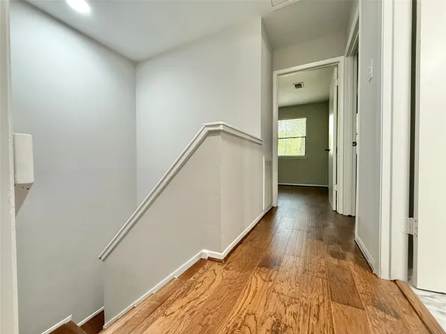 a view of a hallway with wooden floor and staircase