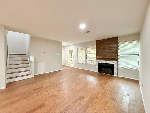 an empty room with wooden floor a fireplace and windows