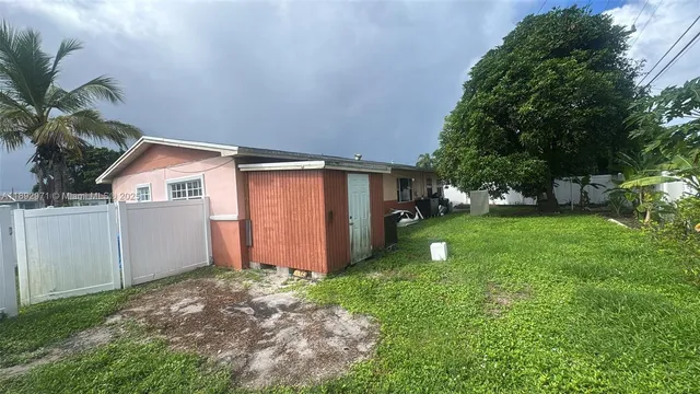 a backyard of a house with plants and large tree