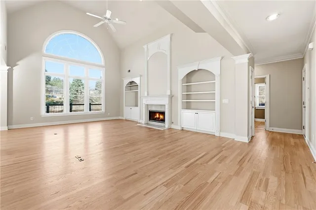 a view of an empty room with a window and wooden floor