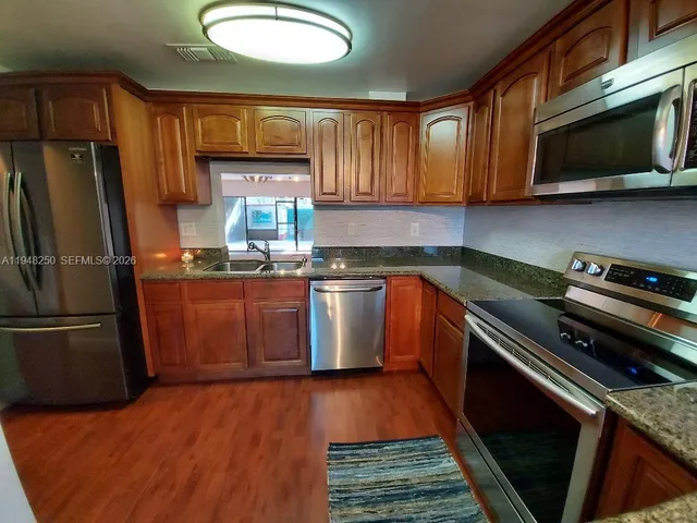 a kitchen with stainless steel appliances granite countertop a stove a sink dishwasher a refrigerator and a microwave