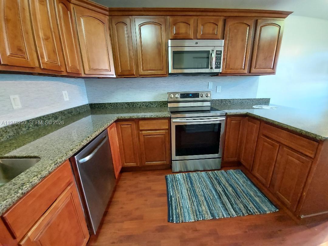 20033 Northeast 2nd Place Miami, FL 33179 - Photo 2 of 23 a kitchen with stainless steel appliances granite countertop a stove a sink and a microwave